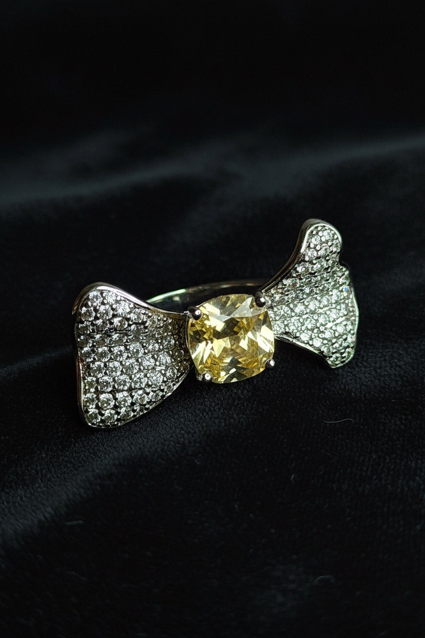 Silver bow-shaped ring with a yellow gemstone