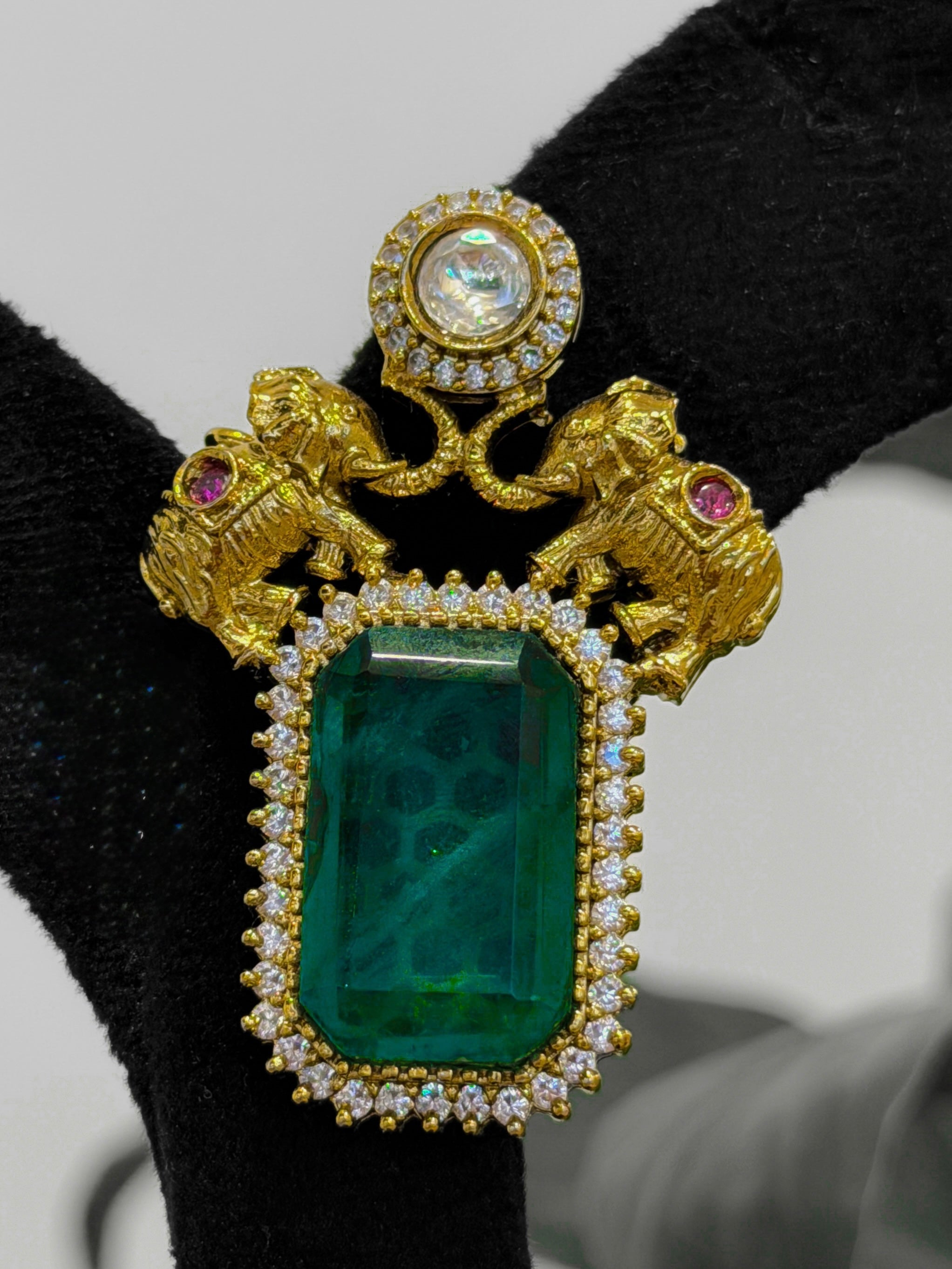 Gold brooch with green gemstone and pink stones