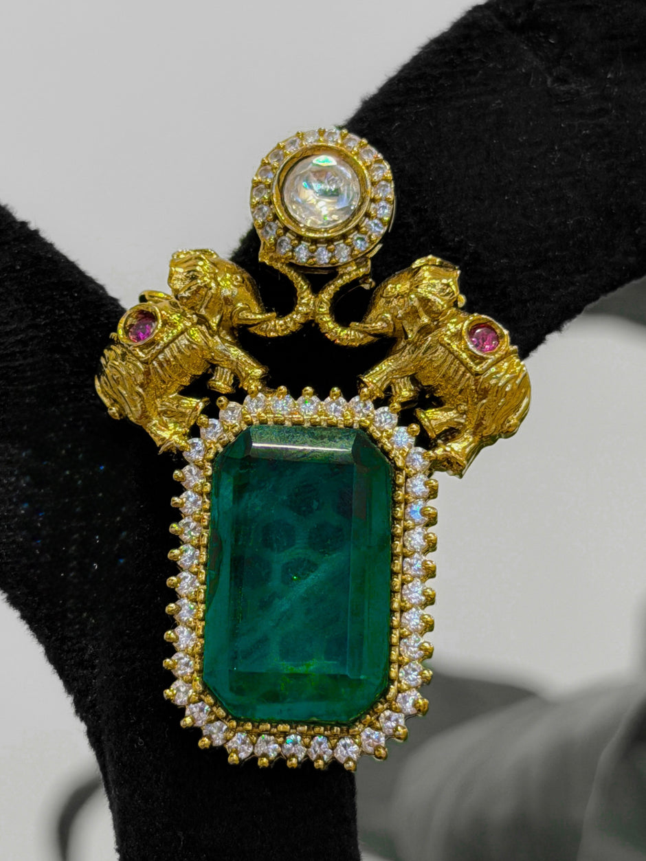Gold brooch with green gemstone and pink stones
