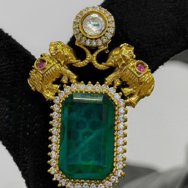 Gold brooch with green gemstone and pink stones
