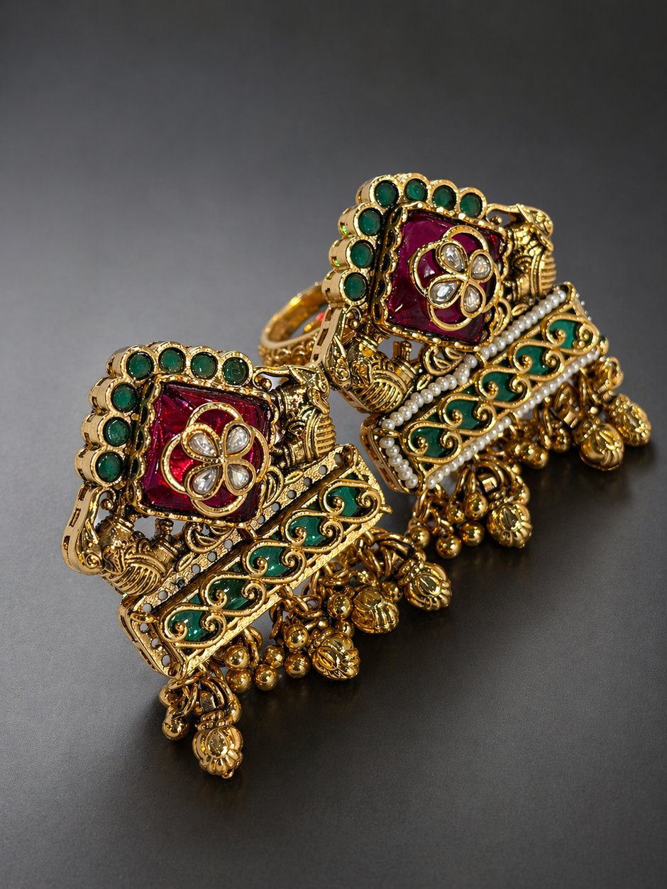 Ornate gold jewelry piece with red and green gemstones 