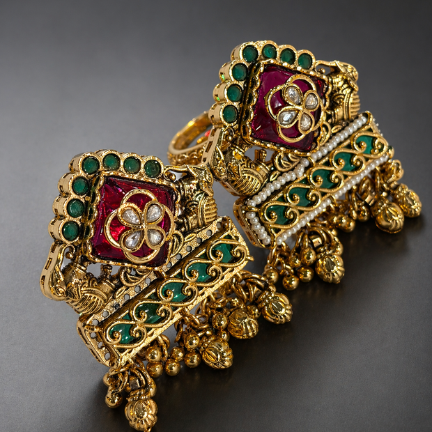 Ornate gold jewelry piece with red and green gemstones 