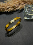 Gold bracelet with engraved text on a dark surface 