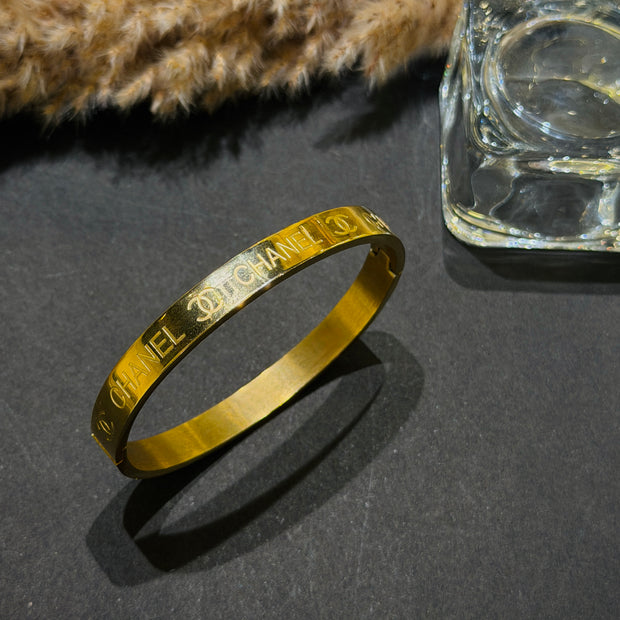 Gold bracelet with engraved text on a dark surface 