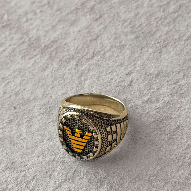 Gold ring with a black and gold emblem 