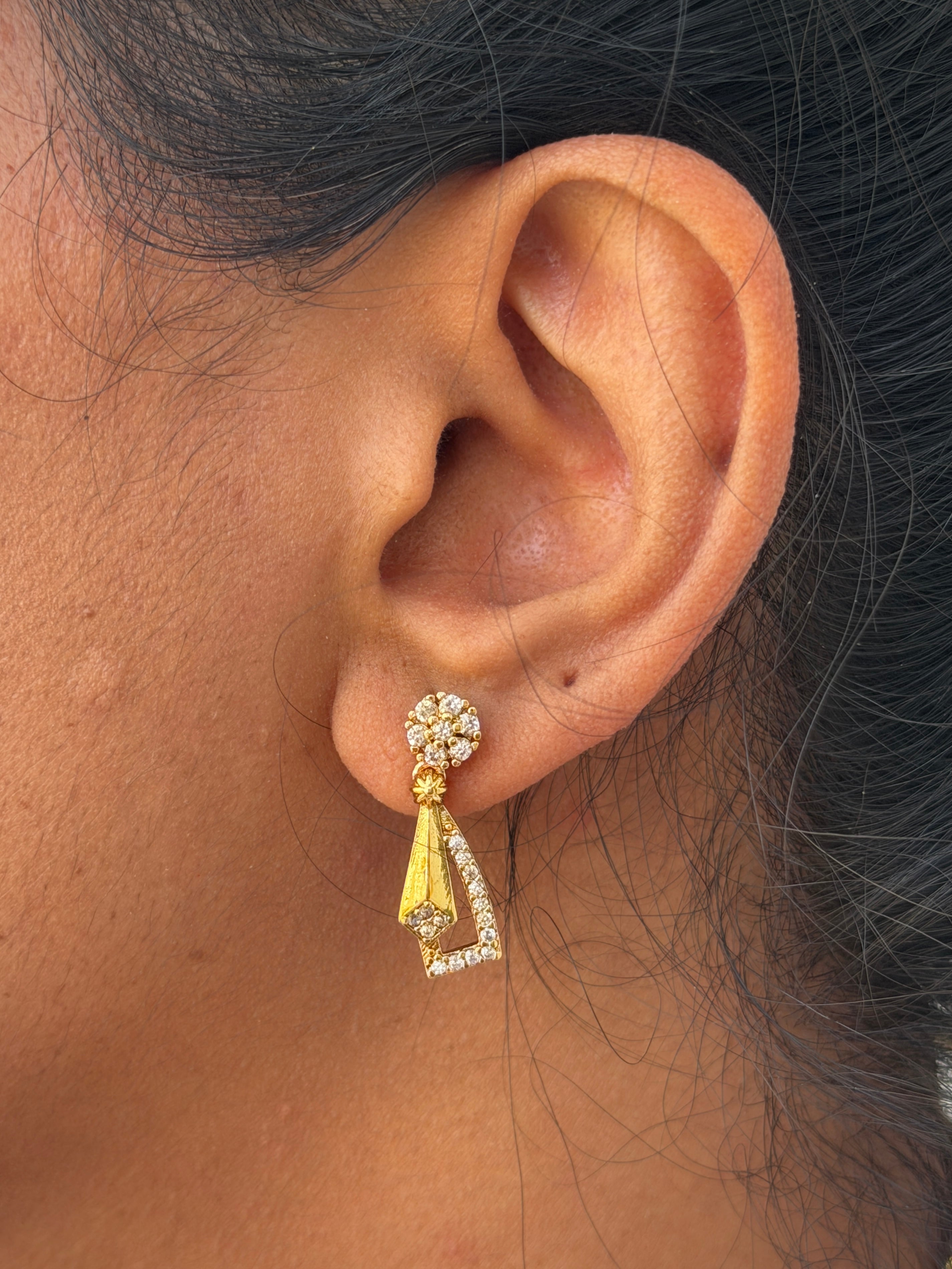ear wearing a gold and diamond earring