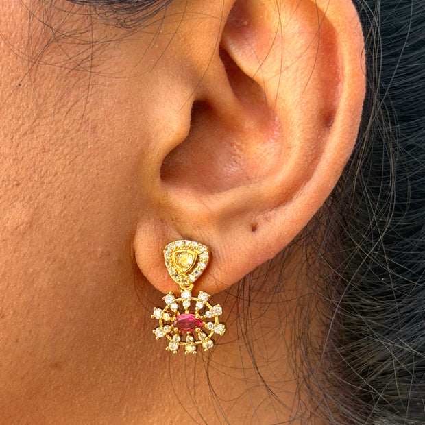 ear wearing a gold earring with a pink gemstone.
