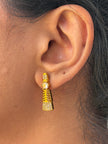 Gold earring worn by a person with dark hair.