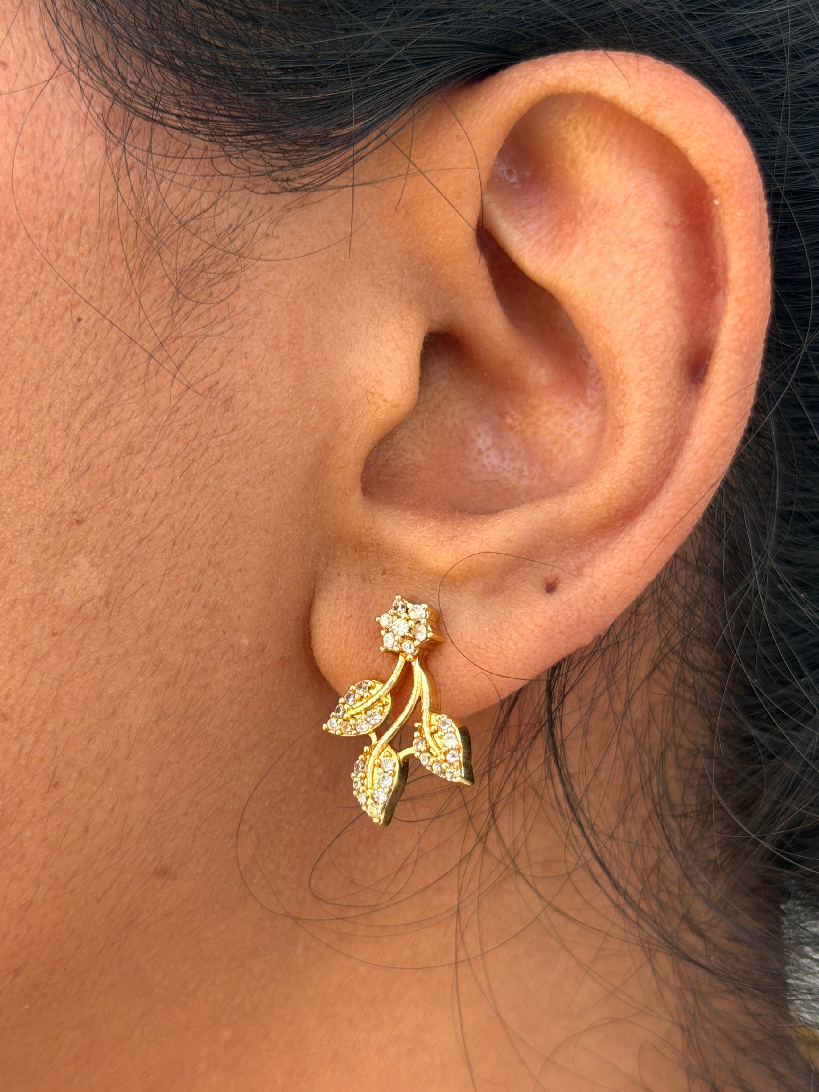 ear wearing a gold earring with leaf design