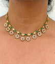 Gold necklace with floral designs and green gemstones 