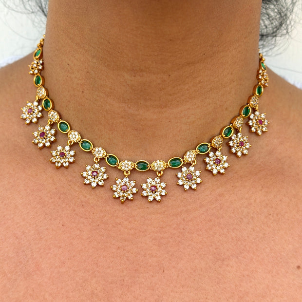 Gold necklace with floral designs and green gemstones 