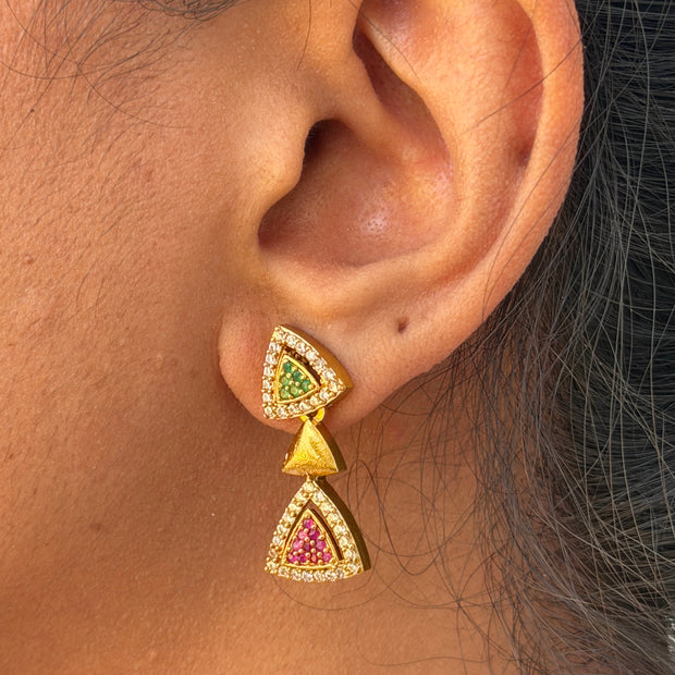 ear wearing a gold and gemstone earring.